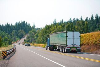 A truck is driving down a wooded country road A truck is driving down a wooded country road